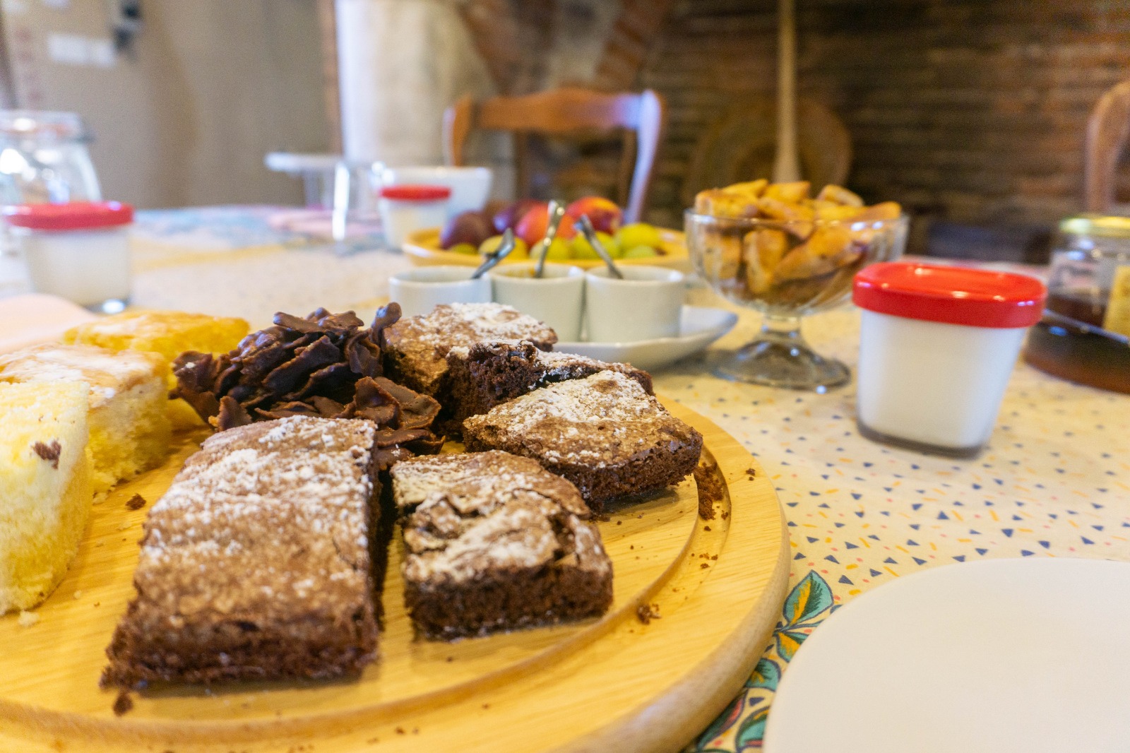 Petit-déjeuner fait maison servi en chambre d'hôtes avec gâteaux, yaourts, fruits frais et confitures artisanales.
